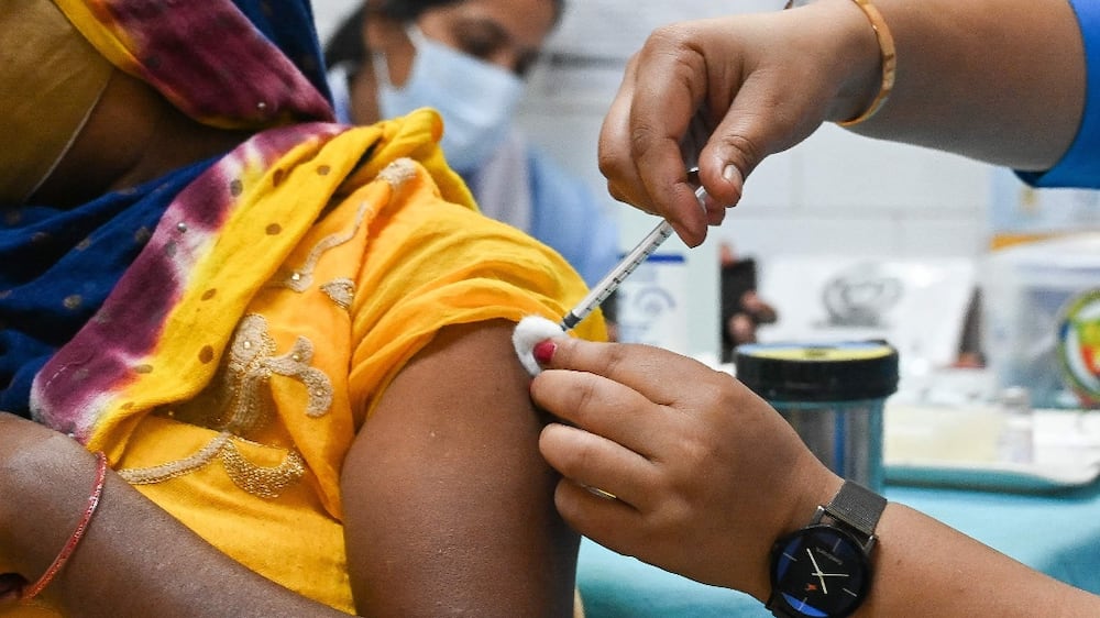 A health worker inoculates a woman with a dose of the Covaxin vaccine against the Covid-19 coronavirus at a health centre in New Delhi on October 21, 2021.  - India administered its billionth Covid-19 vaccine dose on October 21, according to the health ministry, half a year after a devastating surge in cases brought the health system close to collapse.  (Photo by Prakash SINGH  /  AFP)
