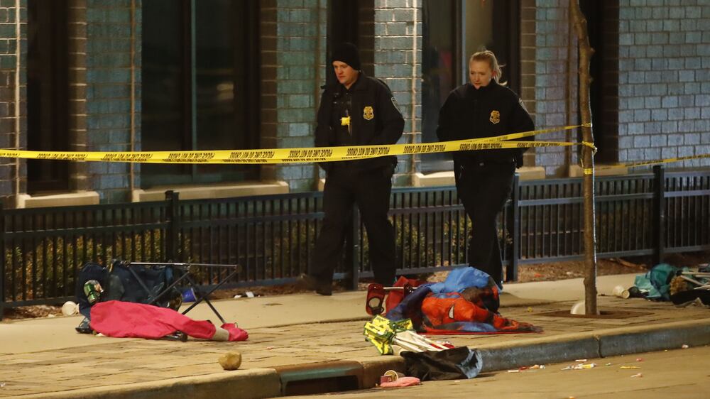 Police officers walk beside debris left from crowds attending a Christmas parade that lies scattered along the route after an SUV reportedly broke through a barricade and drove into people including children leaving several people dead and many more injured in Waukesha, Wisconsin, USA, 21 November 2021.  The vehicle was recovered by police and a person of interest is in custody.   EPA / TANNEN MAURY