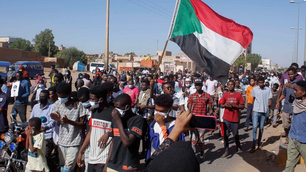 Sudanese protesters lift national flags during a demonstration calling for a return to civilian rule in the capital Khartoum, on November 21, 2021.  (Photo by AFP)