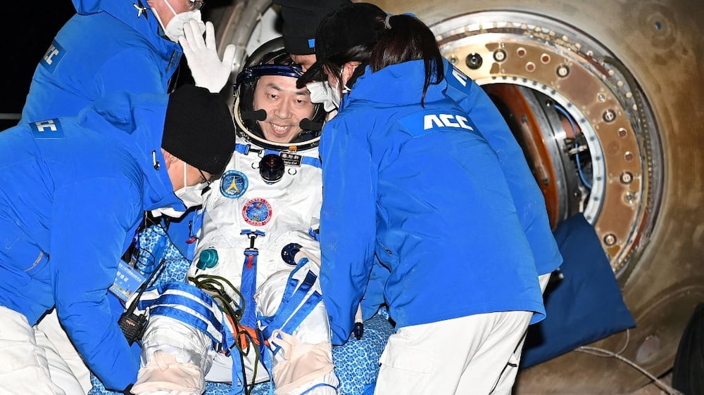 This photo taken on December 4, 2022 shows Chinese astronaut Cai Xuzhe waving as officials assist him from the capsule of the Shenzhou-14 spacecraft after landing in China's Inner Mongolia.  (Photo by CNS  /  AFP)  /  China OUT