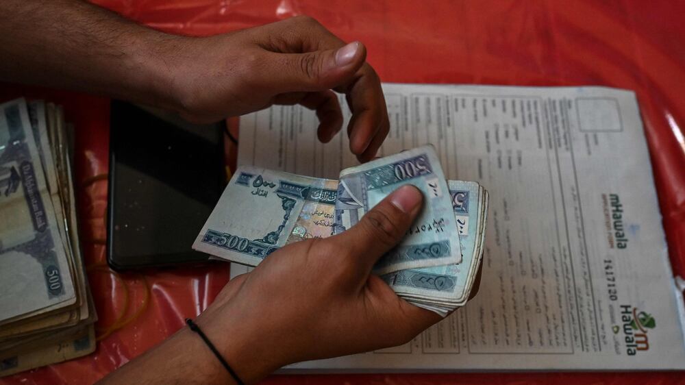 A worker of the World Food Programme counts money during a World Food Programme cash distribution in Kabul on November 29, 2021.  (Photo by Hector RETAMAL  /  AFP)