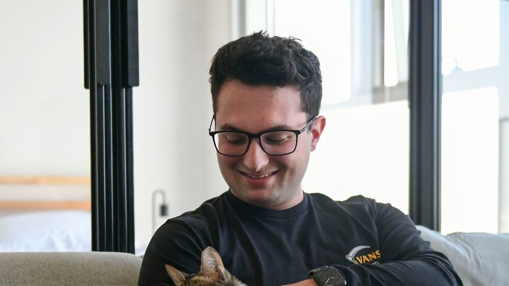 Toby Shaw, 24, with his cat Muteena works as a Investment Property Consultant in his one bedroom apartment at Dubai Hills Estate, Dubai. Khushnum Bhandari / The National