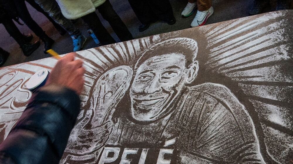 A man draws an image of Brazilian soccer legend Pele with salt as a memorial while people mourn his death at the Pele soccer store in Times Square in the Manhattan borough of New York City, U. S. ,  December 29, 2022.  REUTERS / Eduardo Munoz