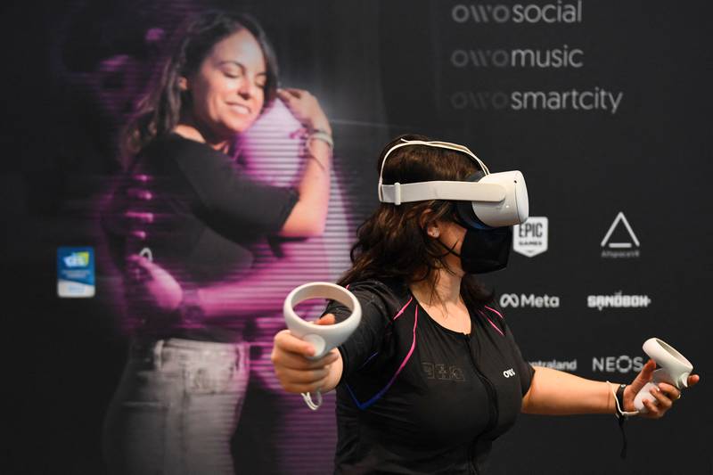 An attendee demonstrates the Owo vest, which allows users to feel physical sensations during metaverse experiences, such as virtual reality games, including wind, gunfire and punching, at CES 2022. AFP