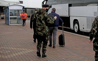 A passenger is escorted to a bus to be taken from the airport in Dublin to the Crowne Plaza hotel for quarantine. Getty Images