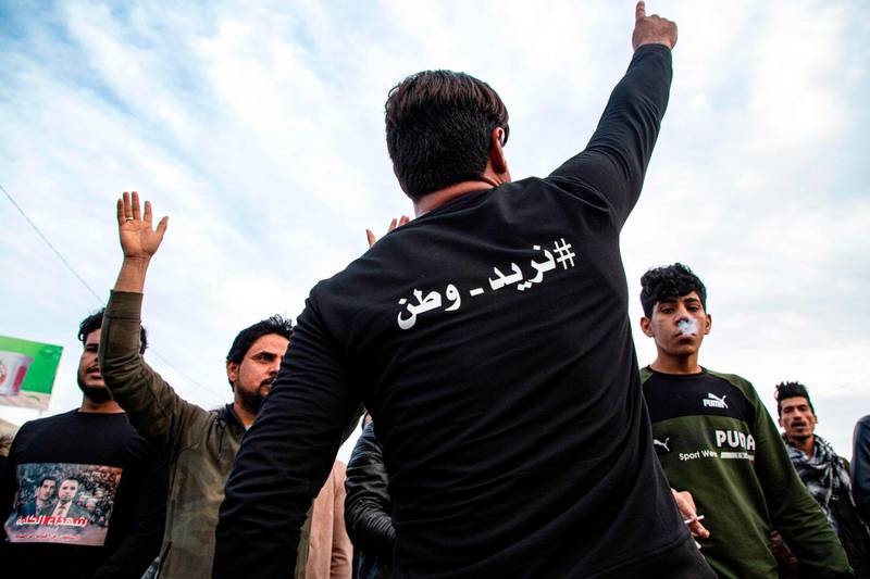 A protester wearing a shirt captioned in Arabic "#We_Want_A_Nation" gestures as others chant slogans during an anti-government demonstration, also calling for freedom of the press, in the southern Iraqi city of Basra.  AFP