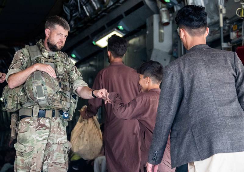 A member of the British military greets a child during evacuation efforts in August 2021 at the Kabul airport in Afghanistan. UK MoD Crown Handout via Reuters