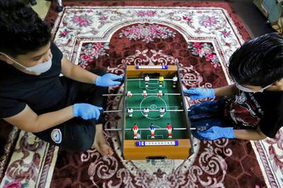 Iraqi children play on a mini table football in their home in the capital Baghdad, as Iraq extends country-wide lockdown until March 28.  AFP
