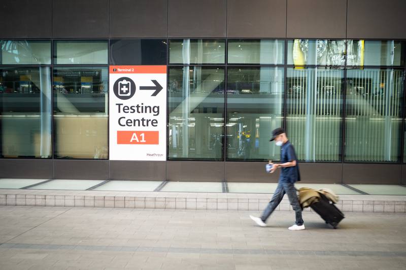 A passenger passes a sign for a Covid-19 testing centre at Heathrow. Arriving travellers have complained of having to pay for tests that go unchecked by UK officials.