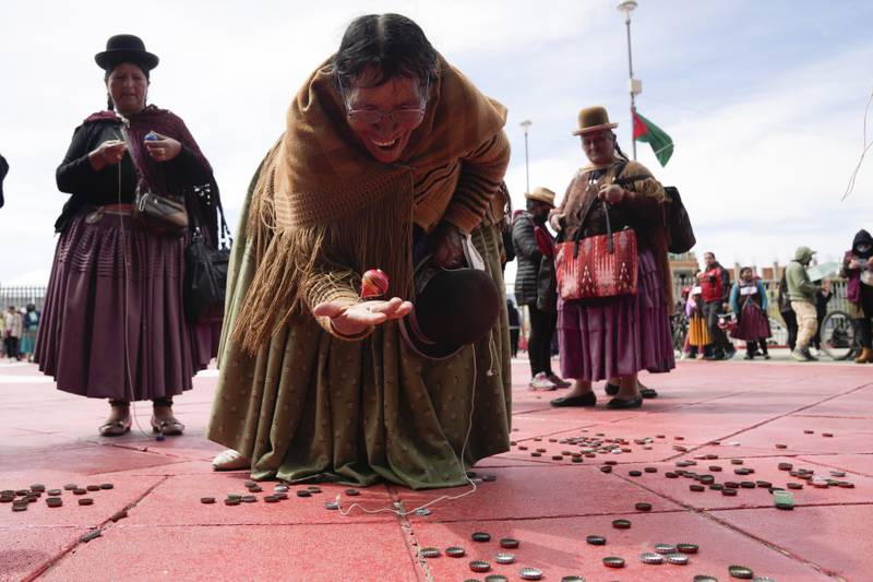 An Aymara woman plays with a spinning top, as part of traditions commemorating the anniversary of the founding of the city of El Alto, Bolivia. AP