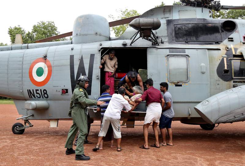 People help a woman disembark from an Indian Navy helicopter at a relief camp. Reuters