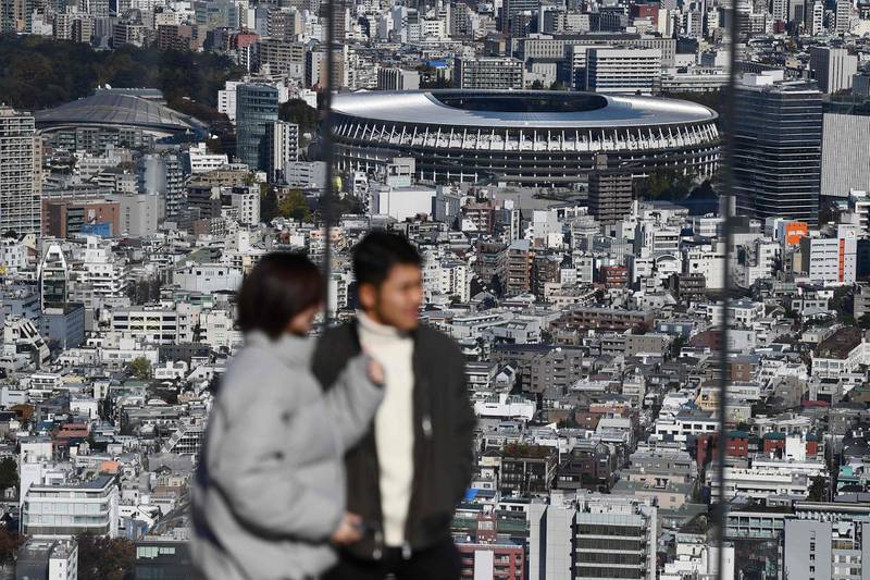 People at a viewing area look out at the completed Tokyo 2020 Olympic Games stadium. AFP