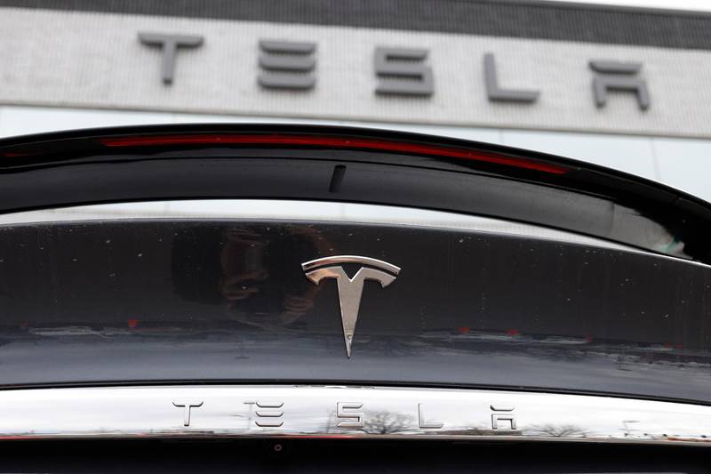 FILE - In this April 26, 2020  photograph, the company logo shines off the rear deck of an unsold 2020 Model X at a Tesla dealership in Littleton, Colo.  Tesla is reassuring its 55,000 employees that it hasn't had a major coronavirus outbreak at company facilities worldwide. In an email to workers sent Wednesday, July 15, the company said that since January it has had fewer than 10 cases of the virus that causes COVID-19 that were transmitted in the workplace.(AP Photo/David Zalubowski, File)