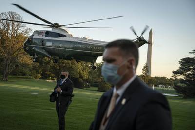 Members of the US Secret Service wear protective masks as Marine One, with U.S. President Donald Trump on board, departs the South Lawn of the White House. Bloomberg