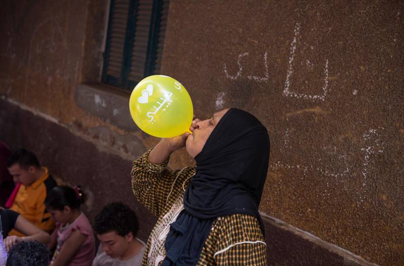 A woman blows a balloon during the installation of Ramadan ornaments at the streets of Giza.EPA
