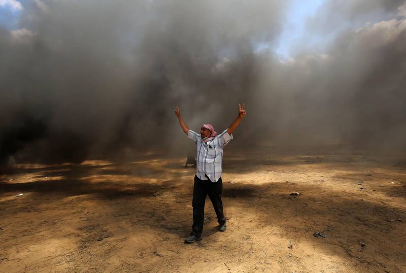 A Palestinian man walks in the smoke billowing from burning tyres during clashes with Israeli forces along the Gaza border. Said Khatib / AFP Photo