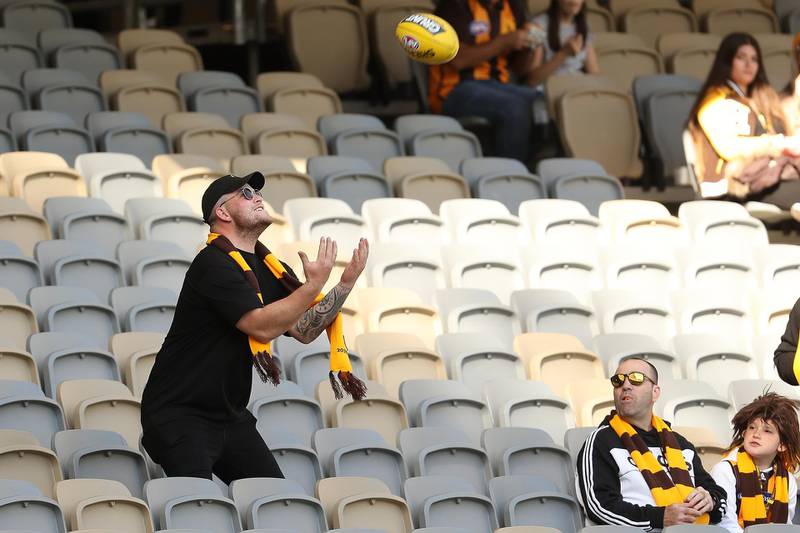 A spectator catches a football kicked by players warming up during round nine of the AFL in a match between the Carlton Blues and the Hawthorn Hawks at Optus Stadium in Perth, Australia. Getty Images