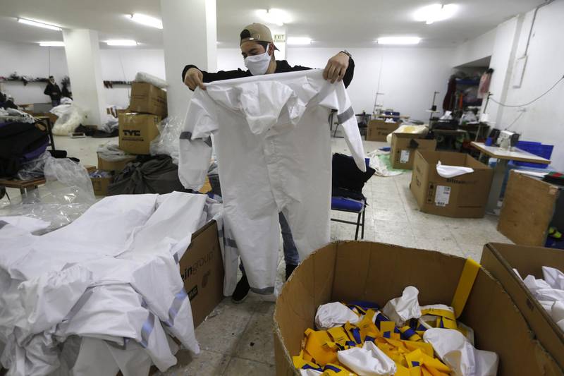 A Palestinian worker holds a protective medical suit in a sewing factory in the West Bank city of Nablus.  EPA