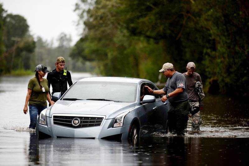 Members of a private critical crisis search and rescue team inspect a vehicle partially submerged in floodwaters during Tropical Storm Florence in Beulaville, North Carolina. Bloomberg
