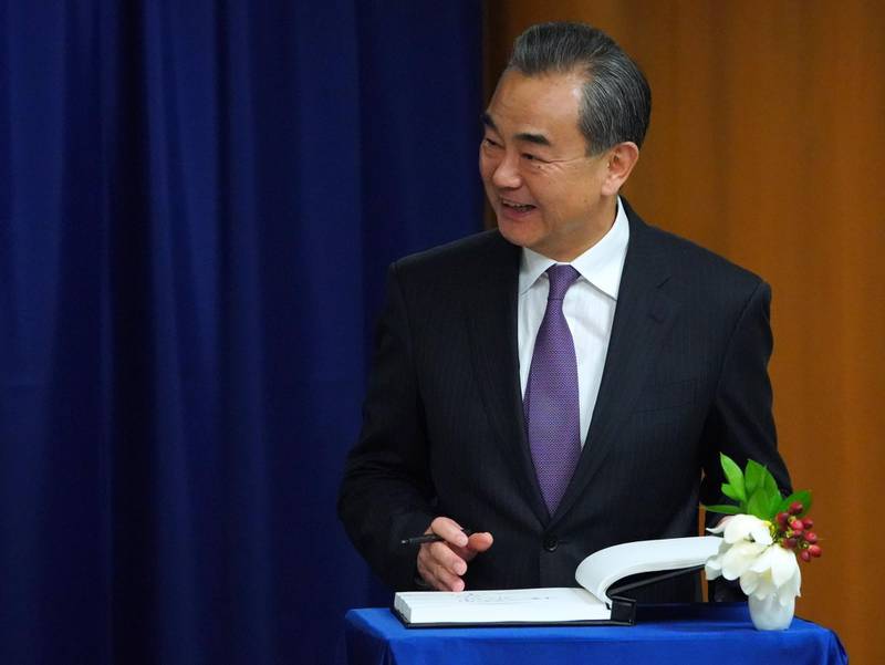China's Foreign Minister Wang Yi signs a book during a meeting with the United Nations Secretary General. AFP