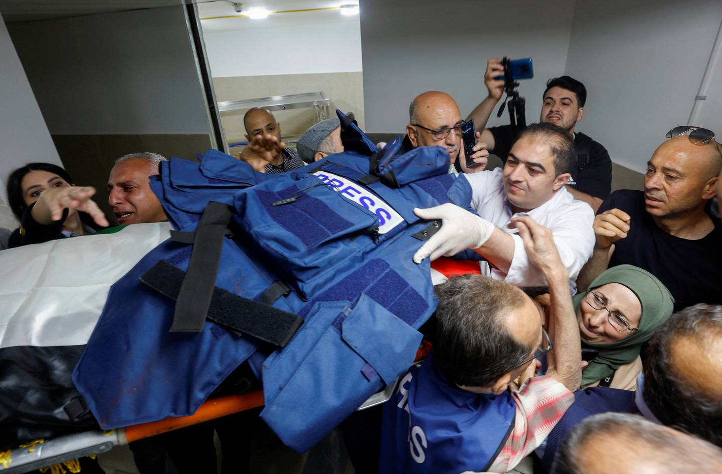 Mourners, including journalists, carry the body and flak jacket of Al Jazeera reporter Shireen Abu Akleh. Reuters