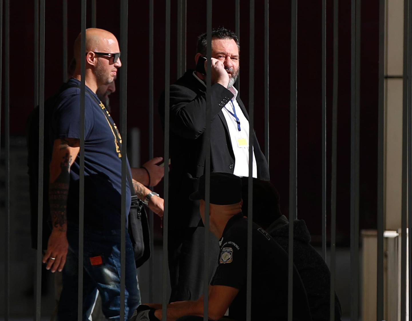 European Parliament member Ioannis Lagos, center, who had been found guilty along with others of leading a criminal organization, and face five to 15 years in prison, uses his mobile phone outside a court, waiting for his sentencing in Athens, Monday, Oct. 12, 2020. An Athens court has extended to Monday a sentencing hearing for leading members and associates of Greece's far-right Golden Dawn convicted earlier this week of multiple crimes. (AP Photo/Thanassis Stavrakis)