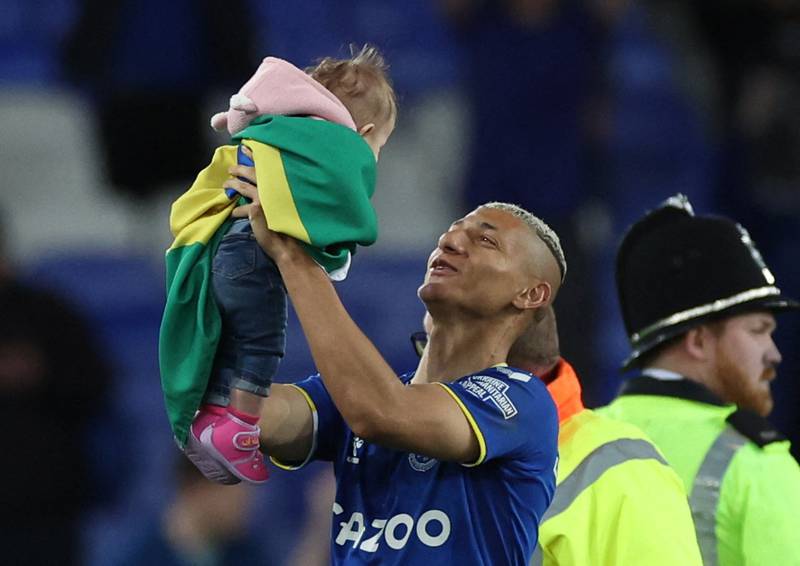 Everton's Richarlison holds a child aloft as he walks around the pitch after the match against Crystal Palace. Reuters