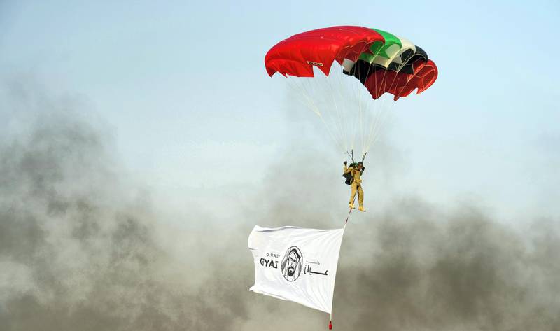 A soldier parachutes down carrying a Year of Zayed banner. Wam