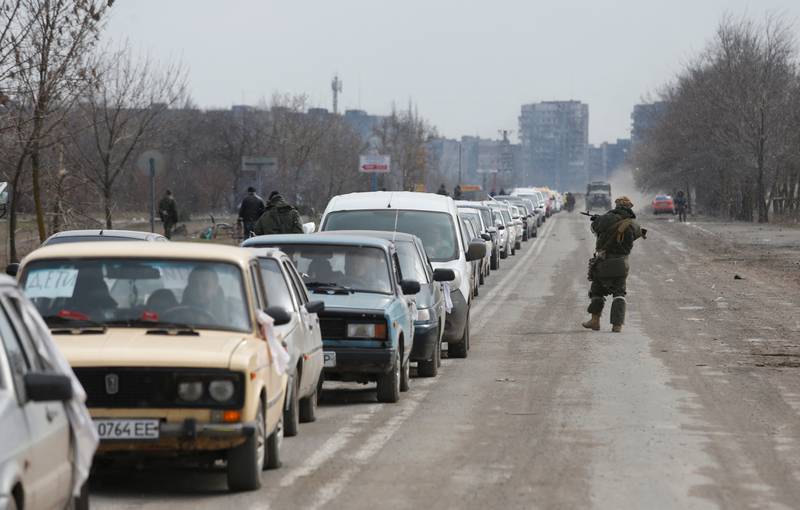 A service member of pro-Russian troops stands guard near a line of cars with evacuees leaving Mariupol. Reuters