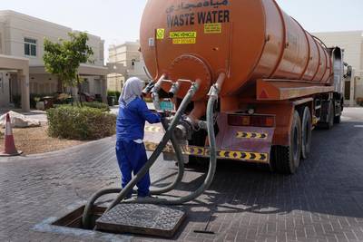 A worker disconnects hoses on a tanker after extracting sewage from a manhole in Al Ghadeer, Abu Dhabi. Delores Johnson / The National