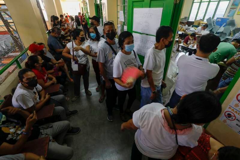 People wait their turn to enter a classroom at a school used as an elections day voting centre in Cainta town. EPA
