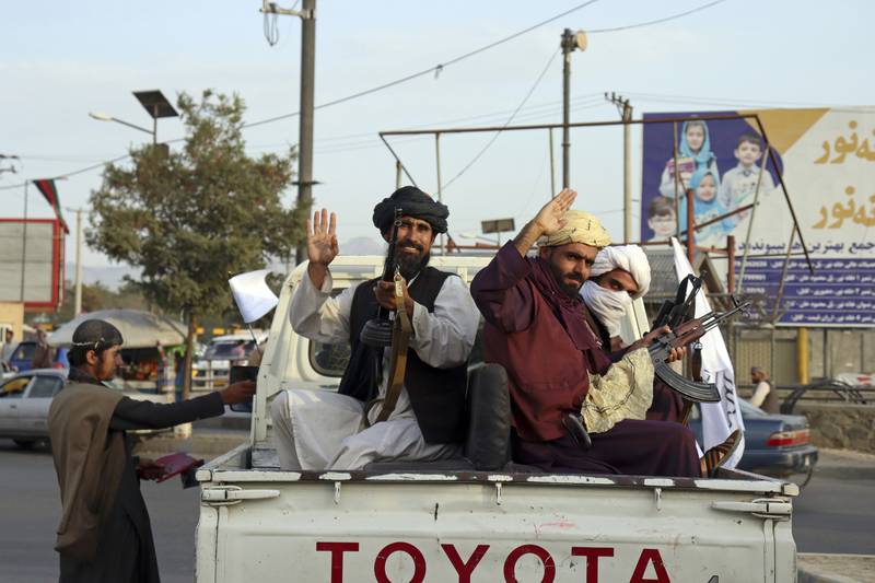 Taliban fighters wave from the back of a pickup truck, in Kabul, Afghanistan, on August 30, 2021. AP