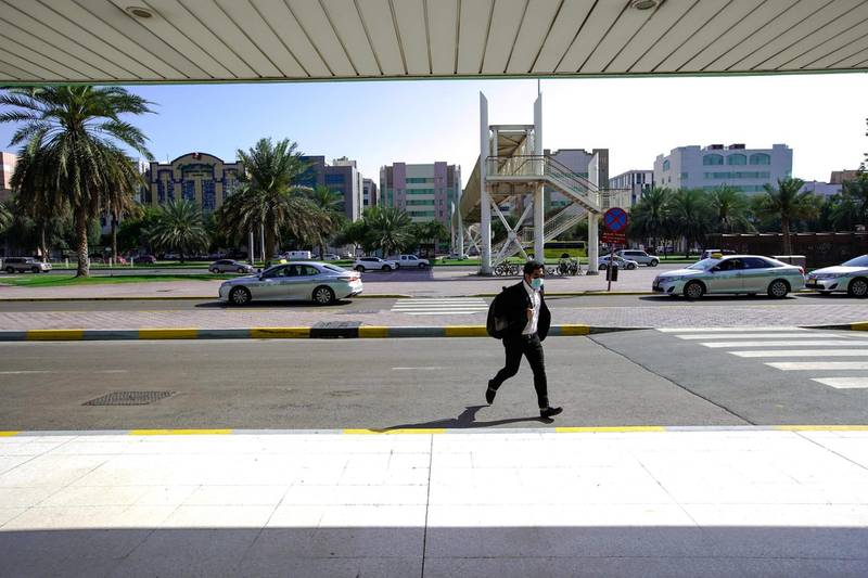 Abu Dhabi, United Arab Emirates, March 24, 2020. Standalone: Coronavirus   A commuter crosses the street at the AUH Central Bus Terminal.  Both automobile and pedestrian traffic has noticeably decreased at downtown Abu Dhabi due to the strict "stay at home" orders the UAE government has implemented to combat the spread of coronavirus.Victor Besa / The NationalSection:  NA