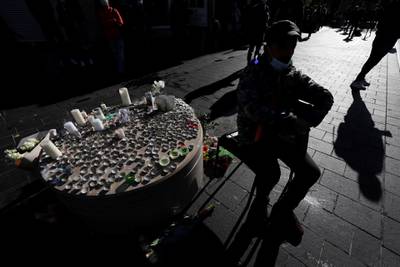 A man sits near candles and flowers placed in tribute to the victims. Reuters