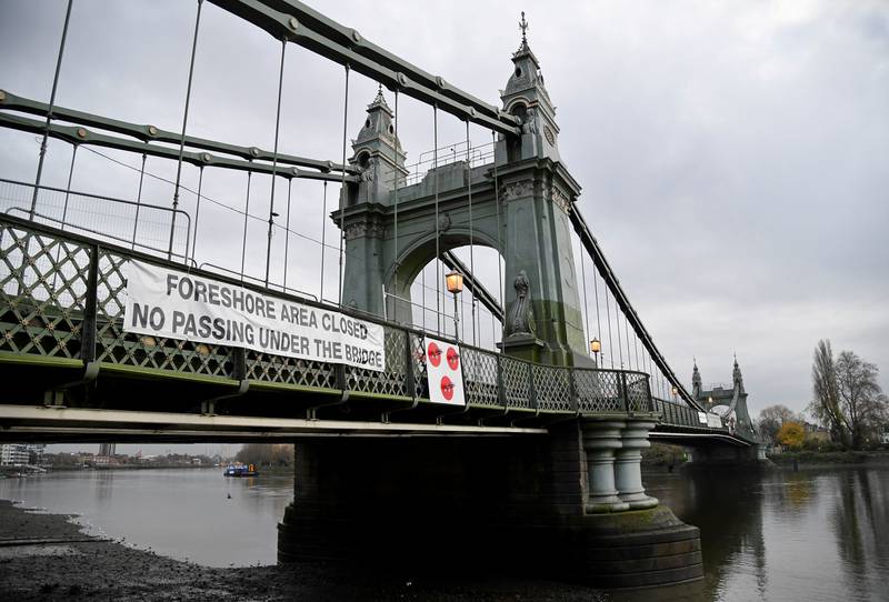 FILE PHOTO: A warning sign is seen attached to Hammersmith Bridge, the closure of which has caused the annual Oxford versus Cambridge boat race on the River Thames, which passes under the now structurally dangerous Victorian bridge, to be relocated outside of London for the first time since World War Two, London, Britain, November 26, 2020. REUTERS/Toby Melville/File Photo