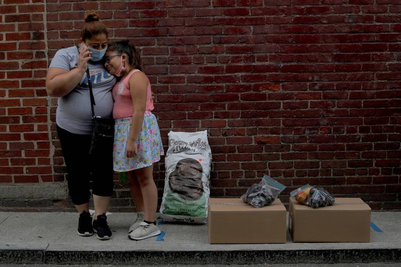 Sandra Cruz, who lost her job because of the Covid-19 outbreak, and fell four months behind on her rent and is fearing eviction, and her daughter Gabriella wait for a ride after picking up free groceries distributed by the Chelsea Collaborative in Chelsea, Massachusetts, on July 22, 2020. Reuters