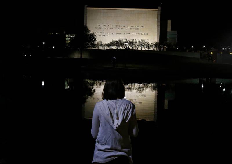 A person stands next to a pond during a candlelight vigil behind the George HW Bush Presidential Library and Museum. EPA