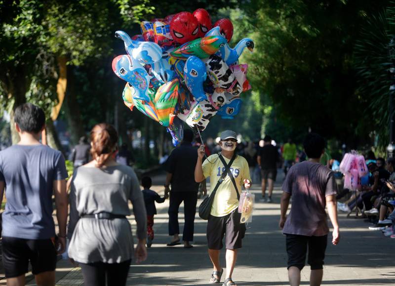 A vendor wears a face mask as he sells balloons near the Bogor Palace in Bogor, Indonesia. The Indonesian government has imposed a new set of regulations known as 'new normal', which will be implemented in stages, starting in early June for some provinces.  EPA