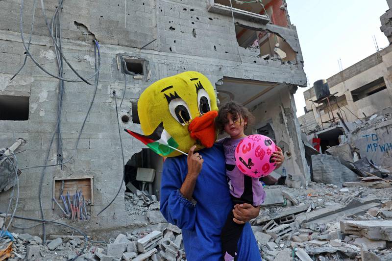 A Palestinian clown carries a child during a show amid the rubble of a building destroyed in the latest round of fighting between Israel and Palestinian militants in Rafah in the southern Gaza Strip. AFP
