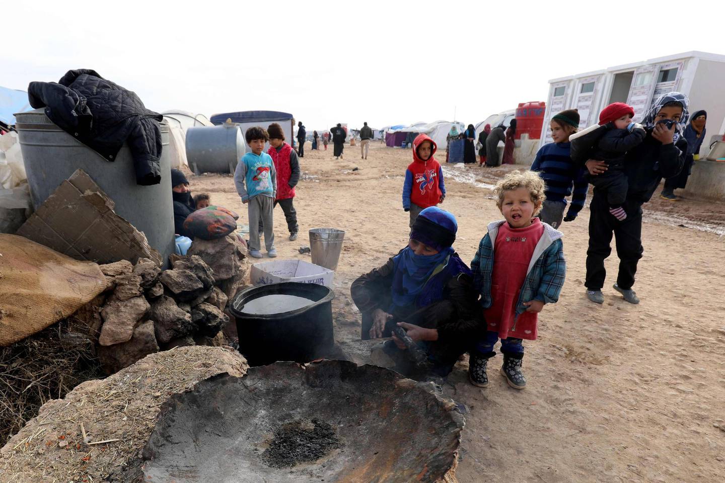 Displaced Syrians, from the eastern city of Deir Ezzor and Raqa who were forced to leave by the war against the Islamic State (IS) group, prepare food at the Ain Issa camp on December 18, 2017.  
As temperatures drop, tens of thousands of civilians forced out of their homes by Syria's war are spending yet another winter in flimsy plastic tents or abandoned half-finished buildings. And without heating, blankets and warm clothes, or access to proper medical care, even a simple cold can turn deadly. / AFP PHOTO / Delil souleiman