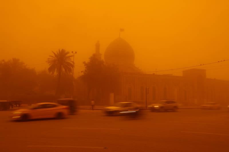 Cars drive by a mosque in Baghdad, barely visible due to the storm. Reuters