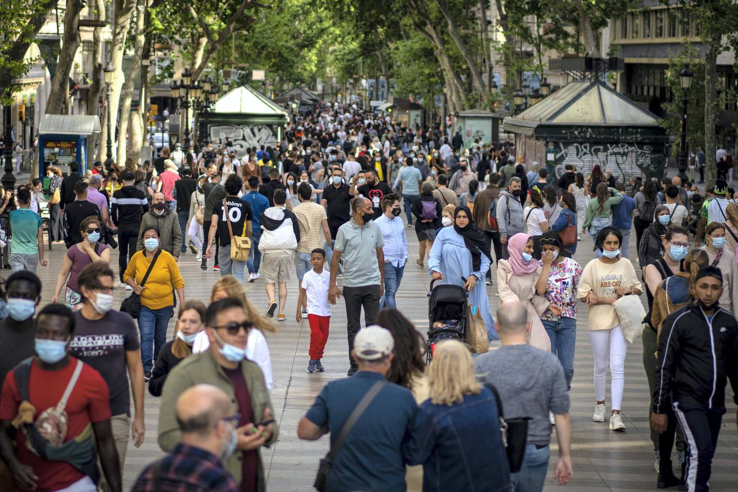 People wearing face masks to protect against the spread of Coronavirus walk along La Rambla in downtown Barcelona, Spain, Saturday, May 15, 2021. (AP Photo/Emilio Morenatti)
