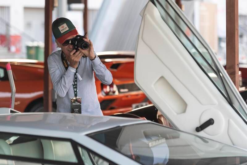 A visitor documents one of the many unique cars on display in the Classic Cars Parking area
