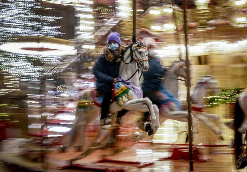 A girl wearing a face mask rides on a merry-go-round at the Christmas market in Frankfurt, Germany. AP Photo