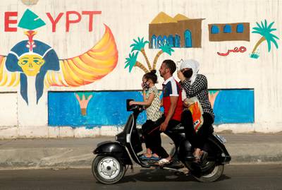 A man rides a motorcycle with his family next to a wall with pharaonic images painted on it, as the spread of the coronavirus continues, in Cairo, Egypt. Reuters