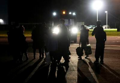 People walk across the tarmac after alighting from a plane from Afghanistan at RAF Brize Norton air base in England.