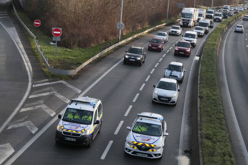Police cars drive ahead of a convoy heading to Paris, in Lille, northern France. AP Photo
