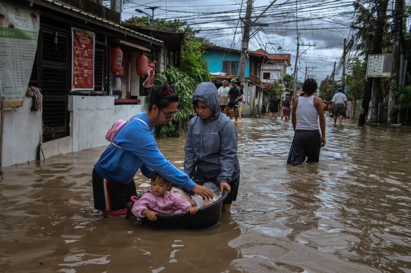 Residents of Kawit village in the Philippines take a child to safety in a tub. AFP