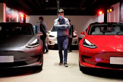 A man walks by Tesla Model 3 sedans and Tesla Model X sport utility vehicles at a showroom in Shanghai. Reuters