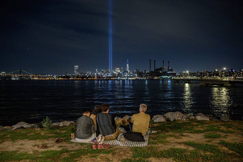 People sit before the east river and the 'Tribute in Light' installation in New York commemorating the 9/11 terrorist attacks. AFP